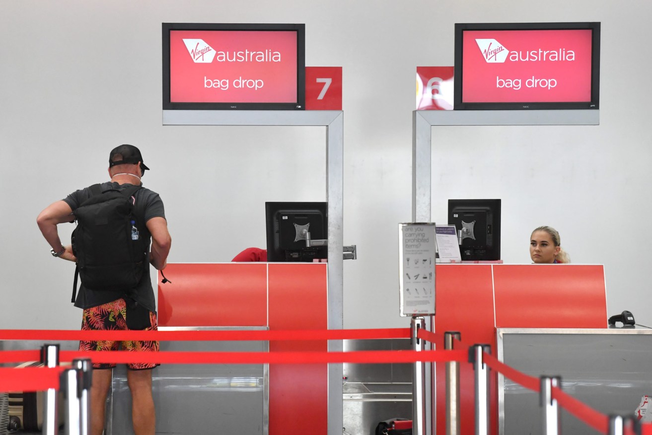 A passenger is seen at the Virgin Australia terminal at the Brisbane Domestic Airport. Virgin Australia has announced it is standing down around 8,000 of its 10,000 workers and will be cutting its domestic capacity by 90 per cent. (AAP Image/Darren England) NO ARCHIVING