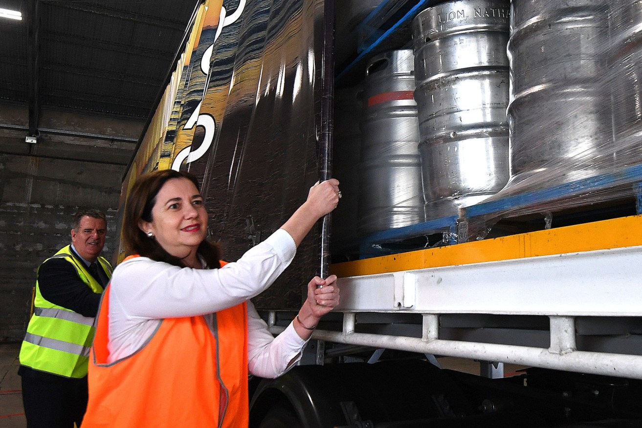 Queensland Premier Annastacia Palaszczuk and the Minister for Agricultural Industry Development Mark Furner, close the covers on a shipment of beer bound for outback Queensland at the XXXX brewery. (AAP Image/Dan Peled) 