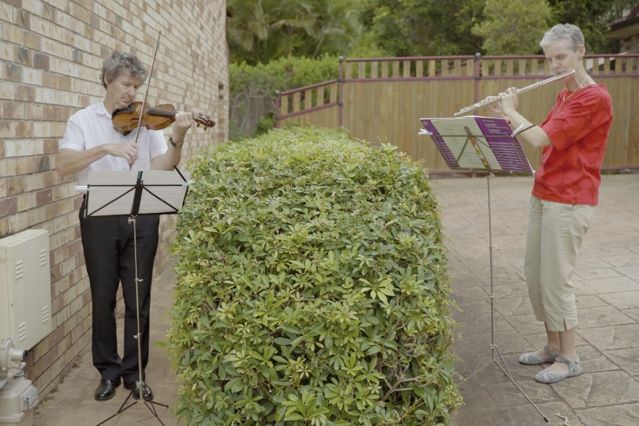 QSO concertmaster Warwick Adeney and section principal flute Alison Mitchell entertain over the fence. (Photo: QSO)
