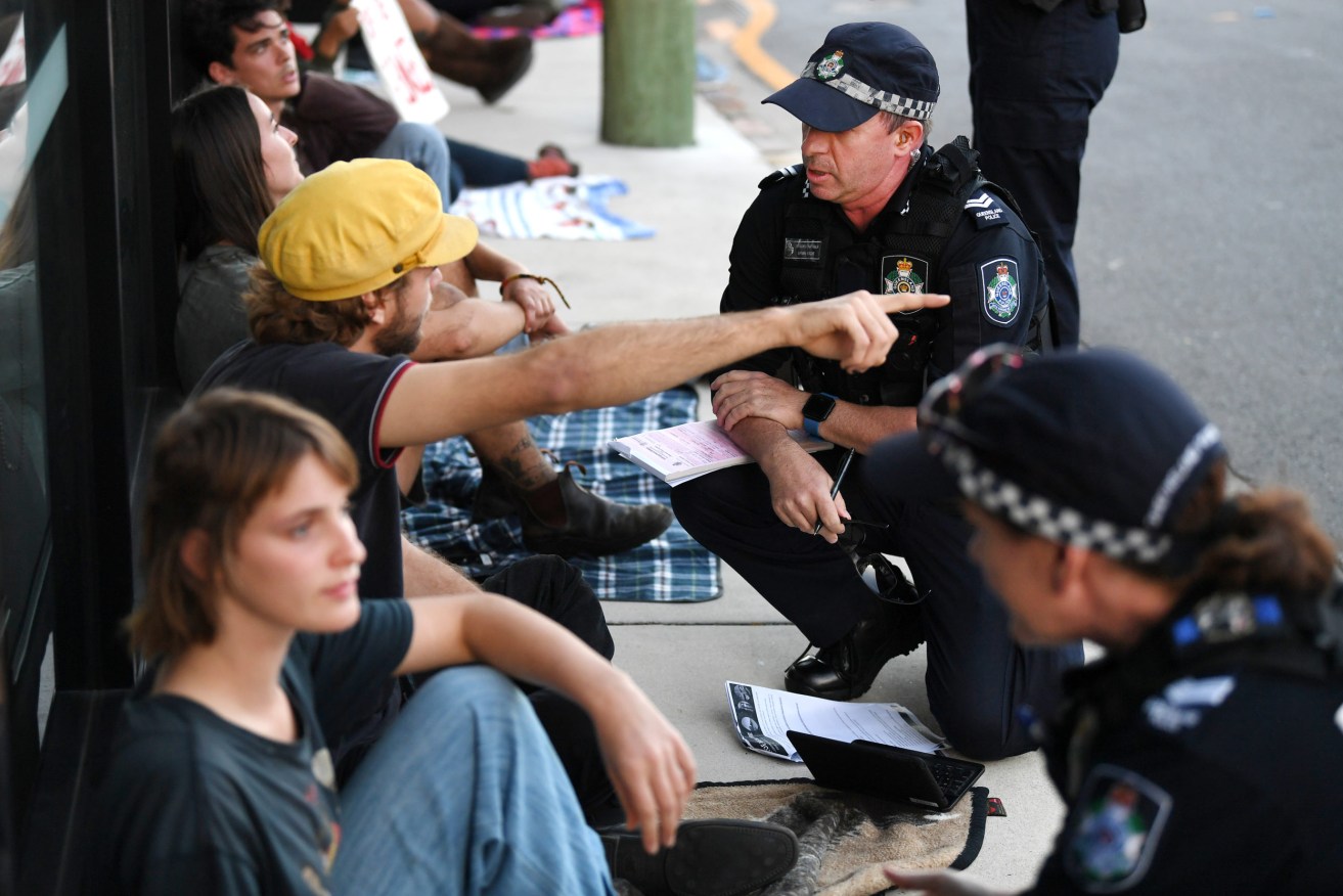 Police officers issues a move-on directive to supporters of asylum seekers who are protesting outside a motel in which they are held in detention in Brisbane, Friday, May 8, 2020. The men claim they are concerned about the spread of the coronavirus (COVID-19) as they cannot maintain adequate social distancing due to the living conditions inside their detention centre. (AAP Image/Dan Peled) NO ARCHIVING