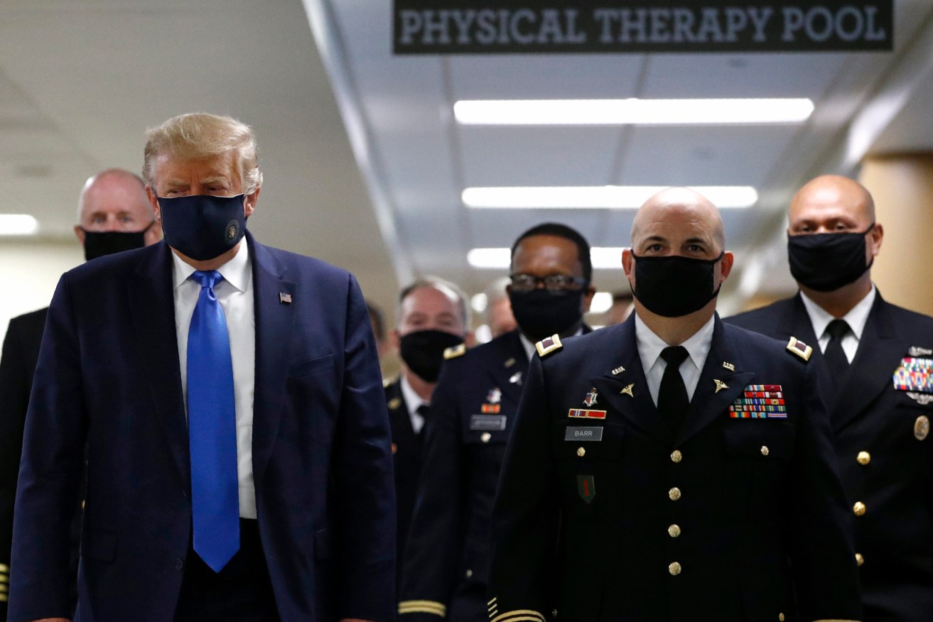 US President Donald Trump wears a face mask as he walks down a hallway during a visit to Walter Reed National Military Medical Center in Bethesda, Maryland on Saturday. (Photo: AP Photo/Patrick Semansky)