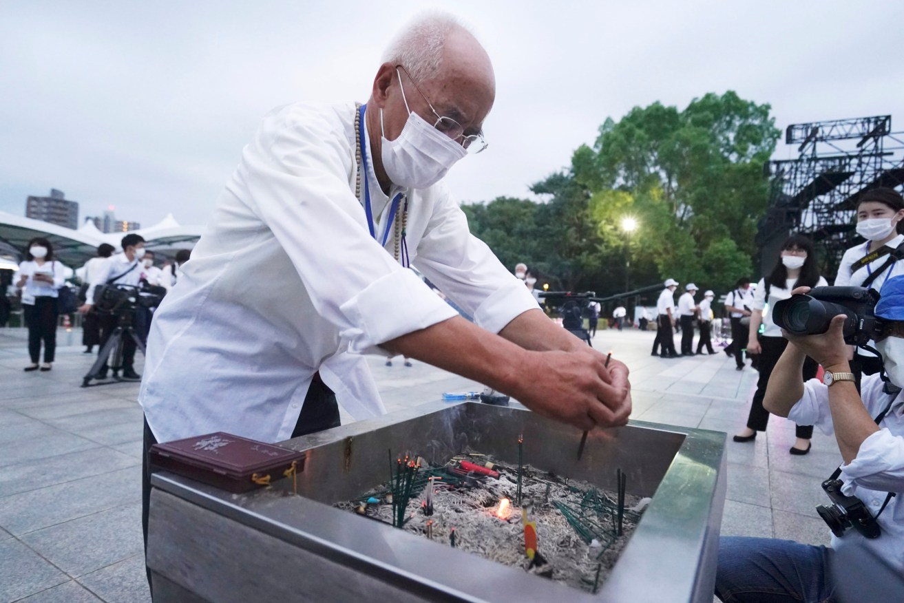 A visitor burns joss sticks in front of the cenotaph for the atomic bombing victims before the start of a ceremony to mark the 75th anniversary of the U.S. bombing in Hiroshima. (AP Photo/Eugene Hoshiko)