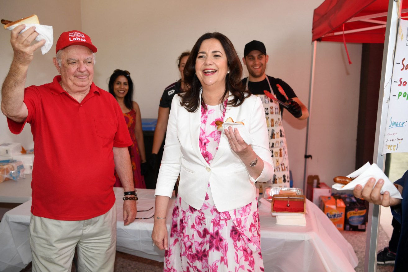 Queensland Premier Annastacia Palaszczuk and her father Henry Palaszczuk enjoy a Democracy Sausage after she cast her vote in the state election, at the Inala State School. (AAP Image/Dan Peled, Pool) 