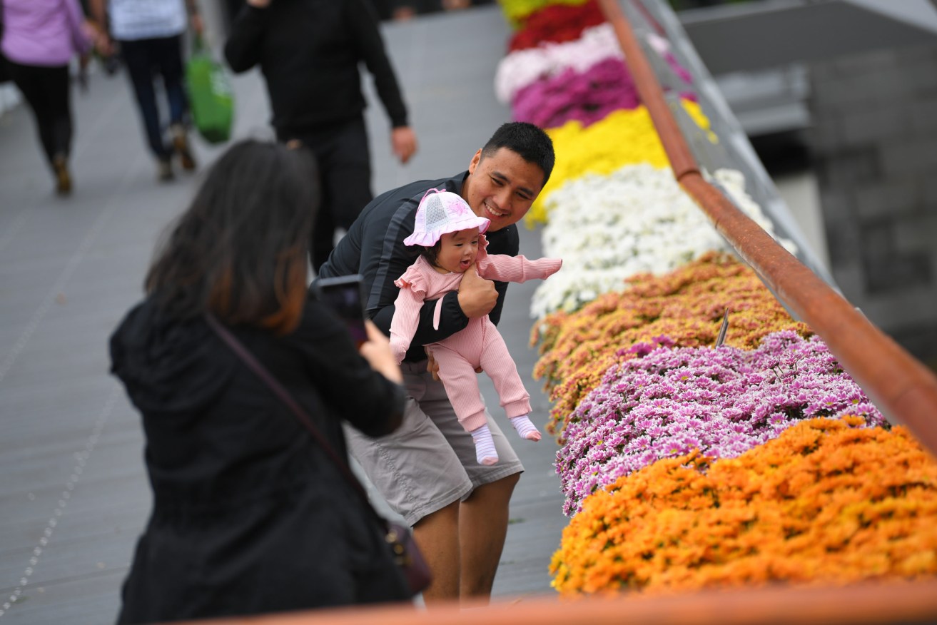 People are seen along Evan Walker Bridge which is lined with flowers in Melbourne, Monday, November 23, 2020. People in Melbourne will be allowed outdoors without wearing a face mask for the first time in months as part of easing COVID-19 restrictions. (Photo: AAP Image/James Ross) 