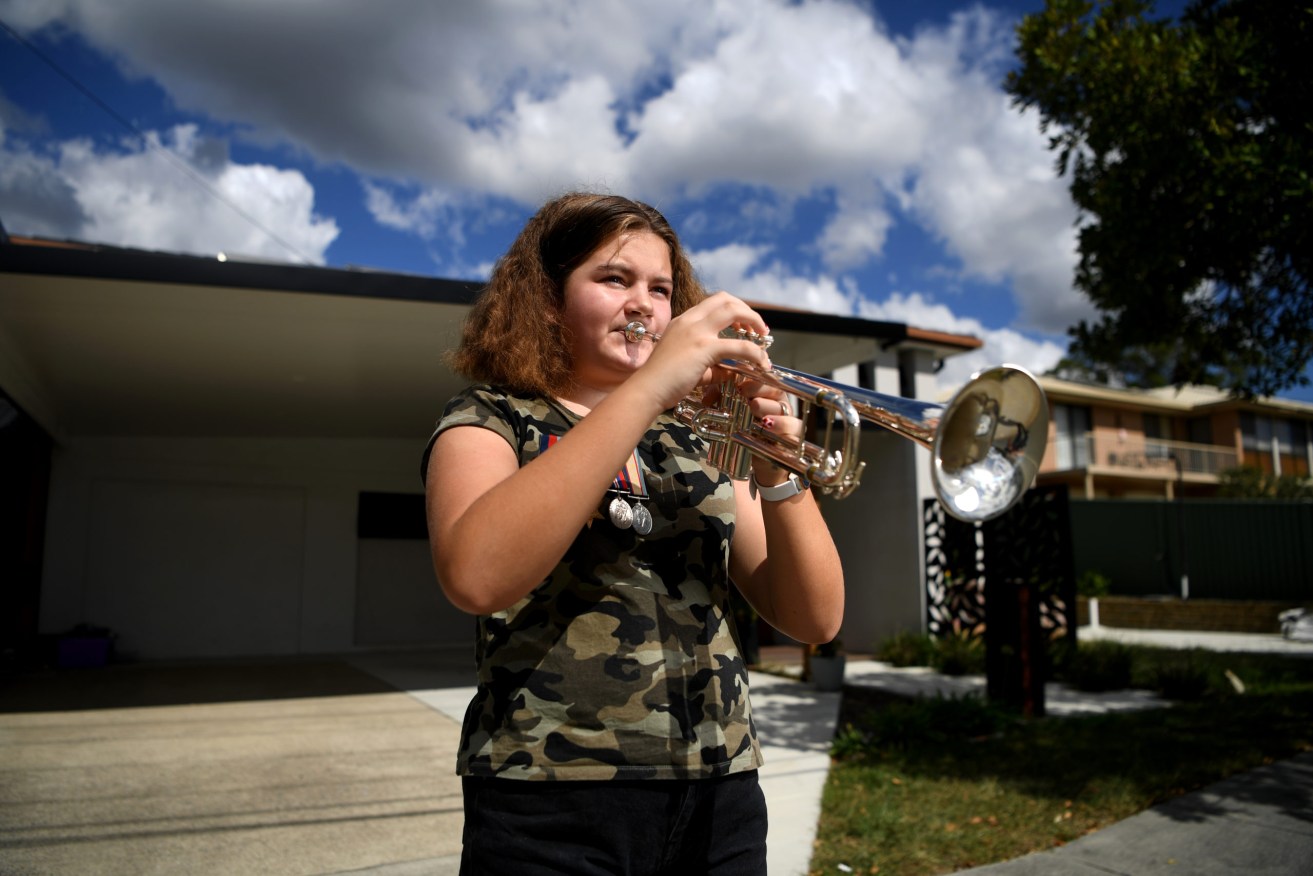 In 2020, when Anzac Day commemorations were restricted due to COVID-19 concerns, Mikaela Gonzalez played the Last Post on her trumpet from her family's driveway in Brisbane. (AAP/Dan Peled) 