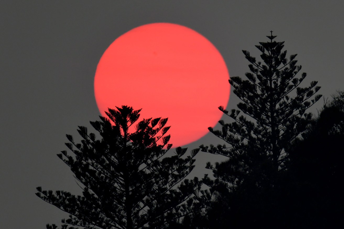 Sunrise is seen through a low band of smoke caused by the Fraser Island bushfires, which have now been burning for more than six weeks. (Photo: AAP Image/Dave Hunt) 