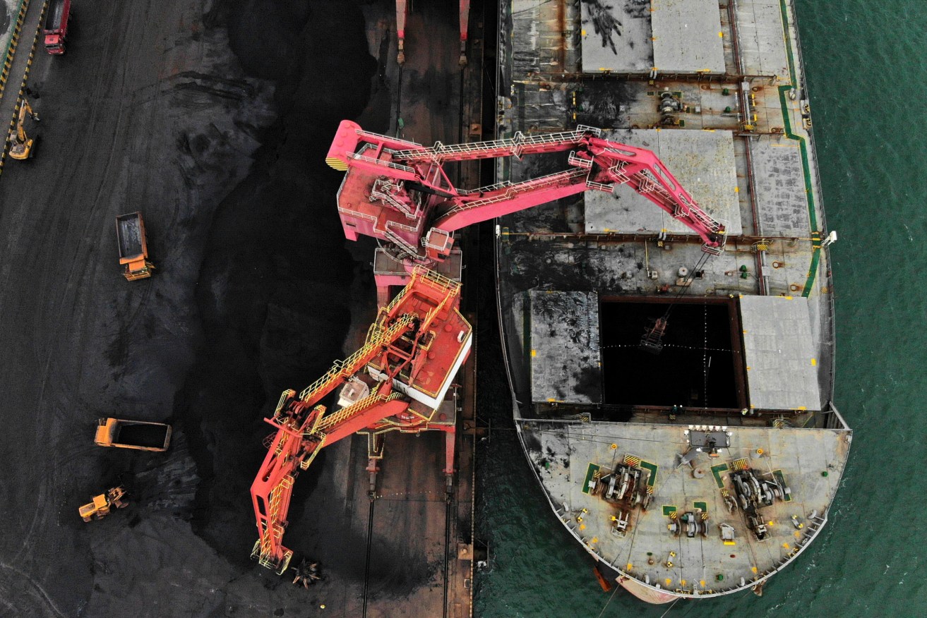 In this photo released by Xinhua News Agency, machines load imported coal from a cargo vessel docked at a port in Rizhao in east China's Shandong province.(Wang Kai/Xinhua via AP)