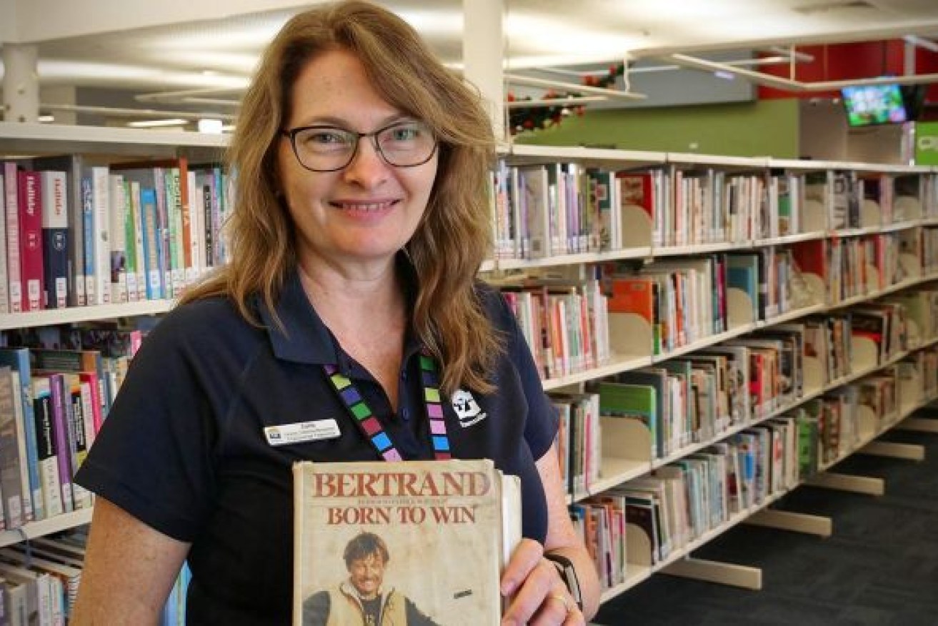 CityLibraries Townsville's Julie Zacchei holds the well-travelled book, which was returned this week — 33 years after being borrowed. Photo: Audience submitted