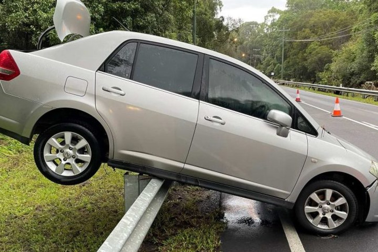 A car was washed onto a guard rail at Thornlands in Brisbane after major flooding impacted southeast Queensland overnight. (Photo: ABC News: Michael Rennie)