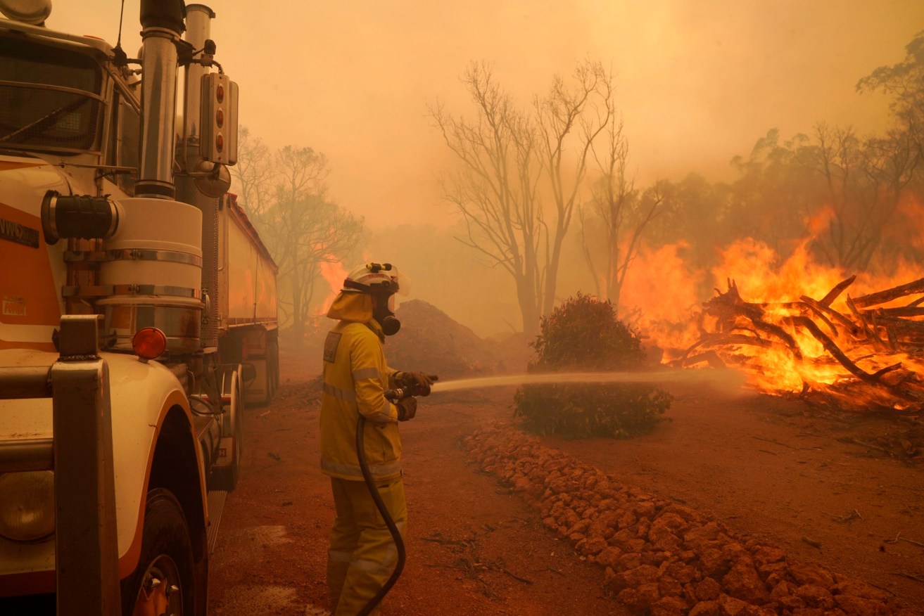 In this photo provided by Department of Fire and Emergency Services, a firefighter attends to a fire near Wooroloo, northeast of Perth. (Photo: Evan Collis/DFES via AP)