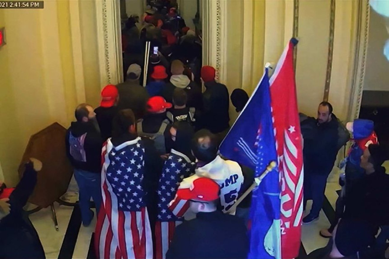 Rioters hold Trump flags as they move inside the Capitol building. Photo: Senate Television/AP
