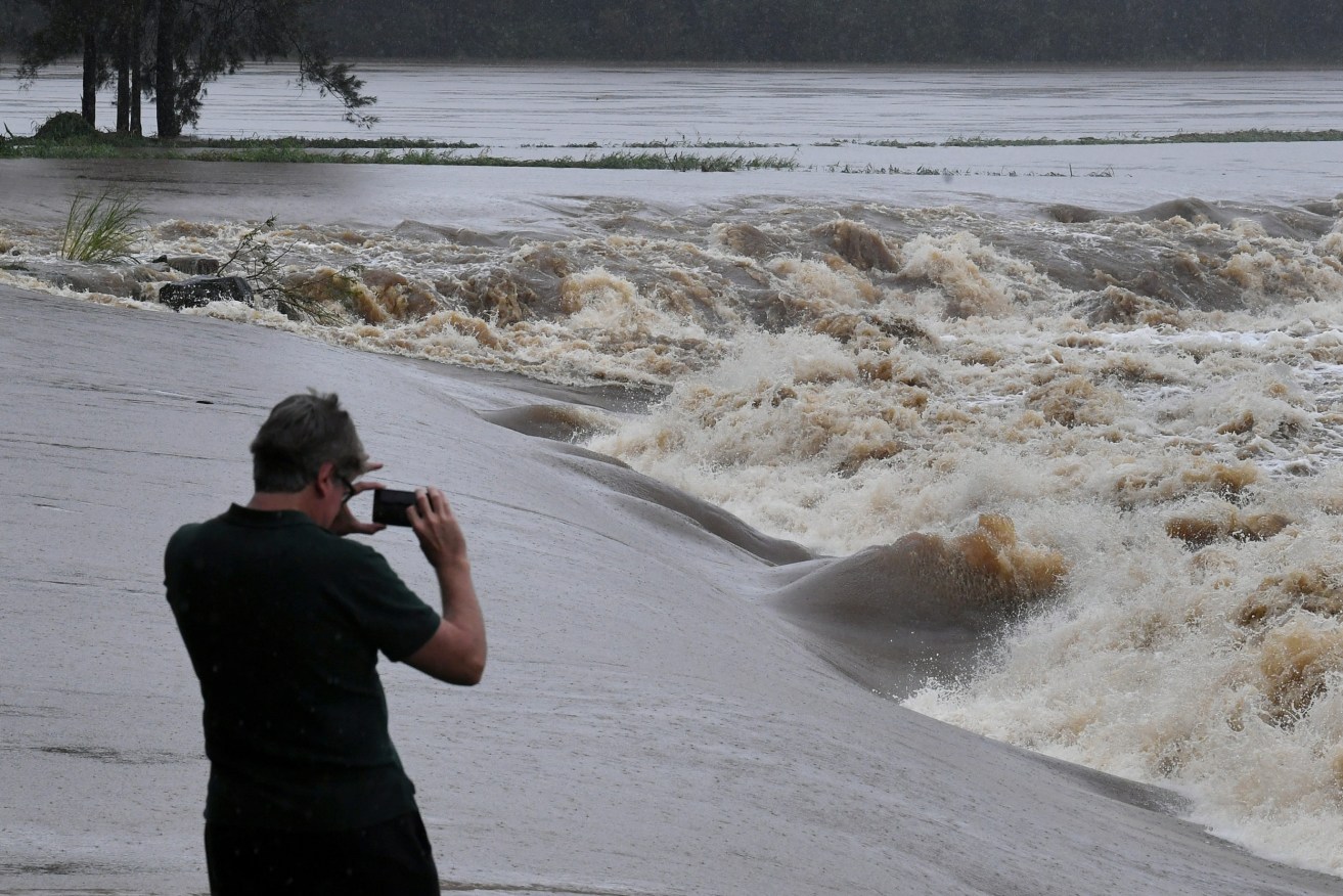 A swollen Coomera River is seen at Oxenford Weir on the Gold Coast. The weather bureau is warning of potentially life-threatening conditions from torrential rain and storms in southern Queensland. (AAP Image/Dave Hunt) 