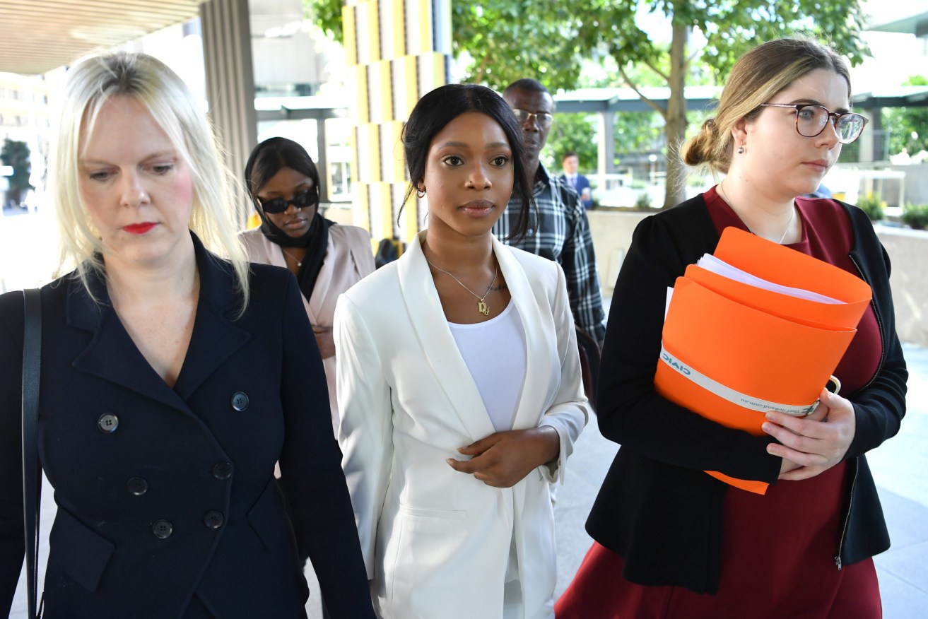 Haja Uma Timbo (centre) is seen arriving at the Brisbane Magistrates Court in Brisbane, Friday.  Timbo and Diana Lasu are being sentenced after being charged with making false statements in border declarations to avoid quarantine after travelling to Melbourne. (AAP Image/Darren England) 