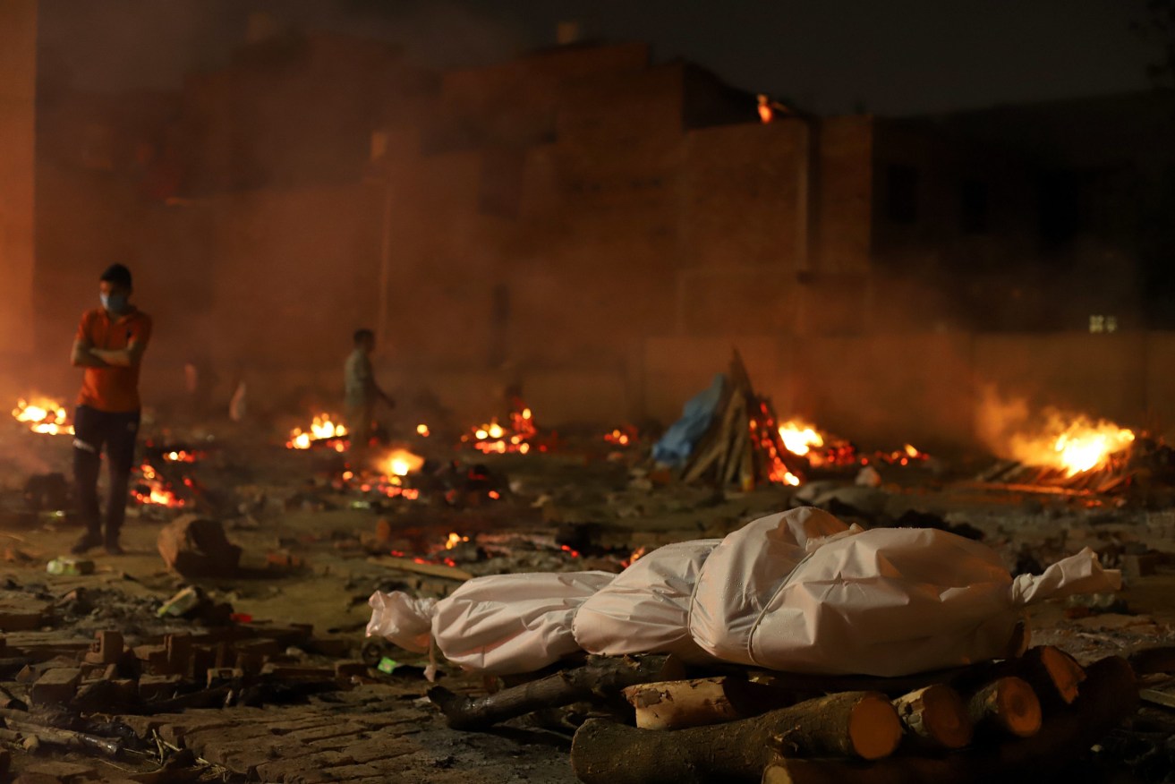 A body lies amid burning pyres of victims at a cremation ground in New Delhi.. India recorded 352,991 new Covid-19 cases and 2,812 deaths in the last 24 hours amid an oxygen crisis. (Photo by Amarjeet Kumar Singh / SOPA Images/Sipa USA)