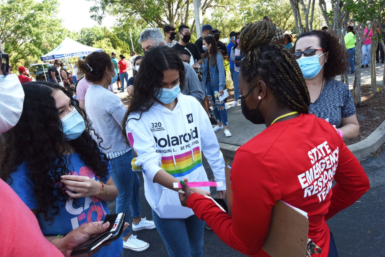 People are issued wrist bands as they wait in line to receive a shot of the Johnson & Johnson vaccine at a pop-up COVID-19 vaccination site in the parking lot at the Mexican Consulate in Orlando. (Photo by Paul Hennessy / SOPA Images/Sipa USA)