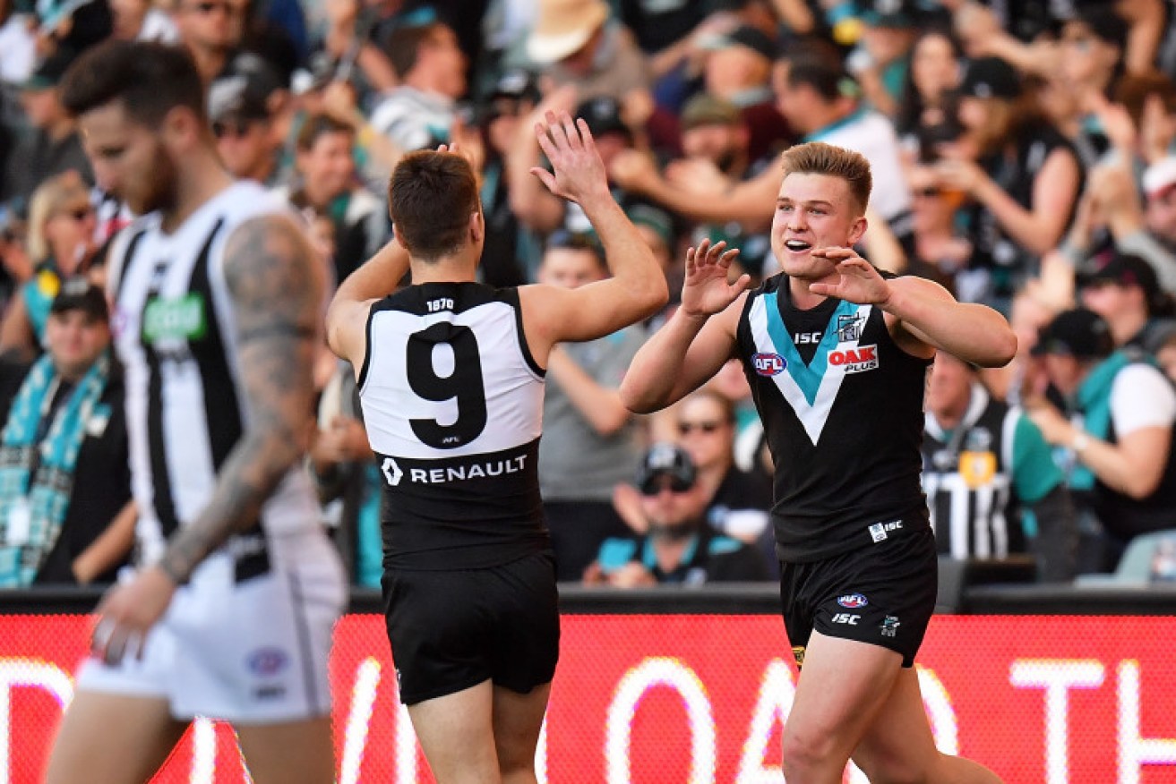Port Adelaide players celebrate a goal in Sunday's AFL match against Collingwood at the MCG. It has been revealed that a man who tested positive as part of the latest coronavirus cluster was at the match (Image: AAP)