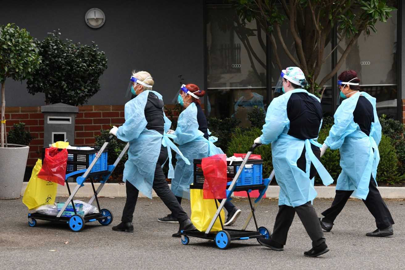 Healthcare workers are seen arriving to the Arcare Aged Care facility in Melbourne. Three latest infections have been found to be from a highly contagious Indian variant. (AAP Image/James Ross) 