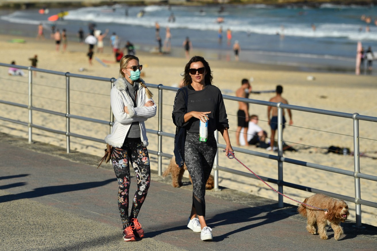 People exercise on the boardwalk at a near-deserted Bondi Beach. More than five million people in Greater Sydney and its surrounds have gone into a 14-day lockdown. (AAP Image/Joel Carrett)