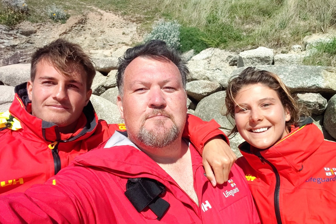 British-based Noosa lifeguard Tori Farmer (right), her fellow Cornwall lifesaver Alex (left) and retired cop Jon Marshall, the man they saved from the treacherous English waters (Image: Supplied)