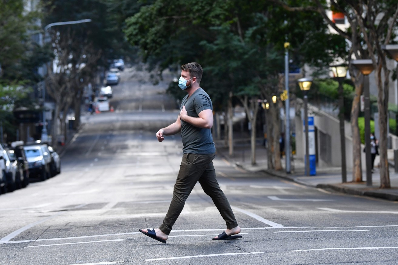 A man is seen crossing an empty Charlotte Street in Brisbane.  The lockdown for Brisbane and Moreton LGAs has been extended for a further 24 hours. (AAP Image/Darren England)