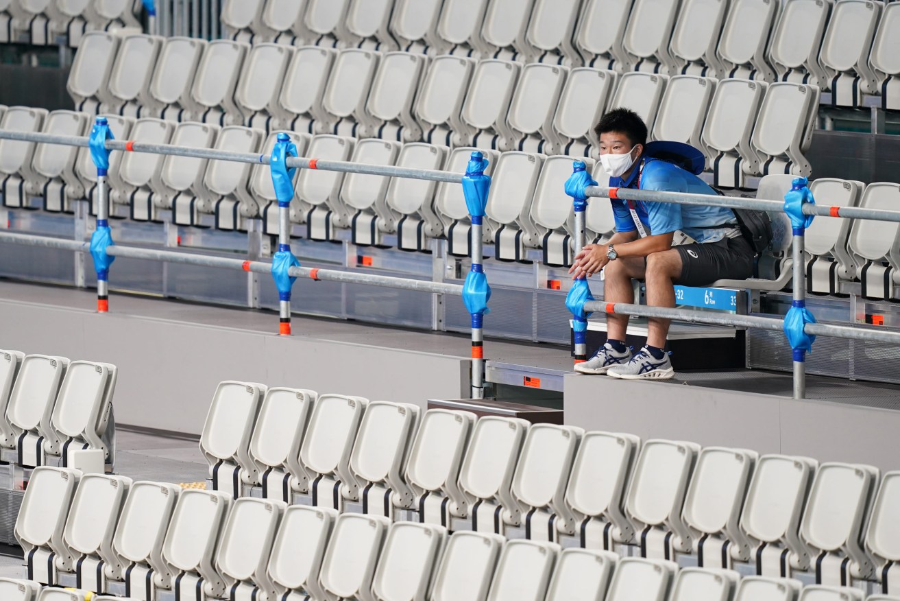 A volunteer sits among the empty spectator seating during the Women’s Water Polo Group A match between Canada and Australia at the Tatsumi Water Polo Centre during the Tokyo Olympic Games, in Tokyo (AAP Image/Joe Giddens) 