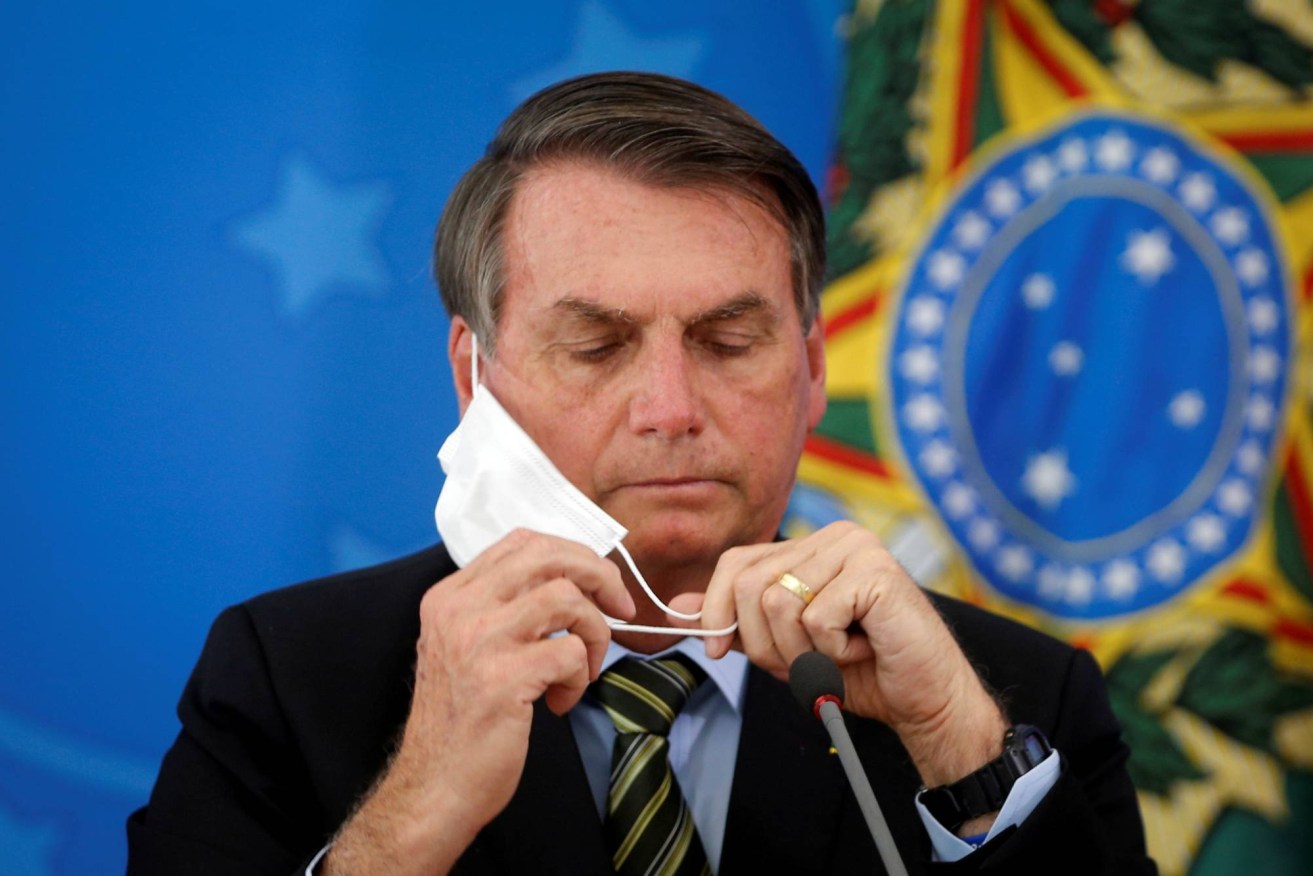Brazil's President Jair Bolsonaro adjusts his protective face mask during a press statement to announce federal judiciary measures to curb the spread of the coronavirus REUTERS/Adriano Machado/File Photo