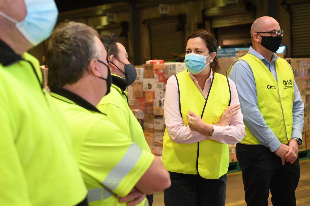Queensland Premier Annastacia Palaszczuk (centre) is seen talking to workers during a press conference at the Woolworths regional distribution centre at Larapinta. (AAP Image/Darren England) 