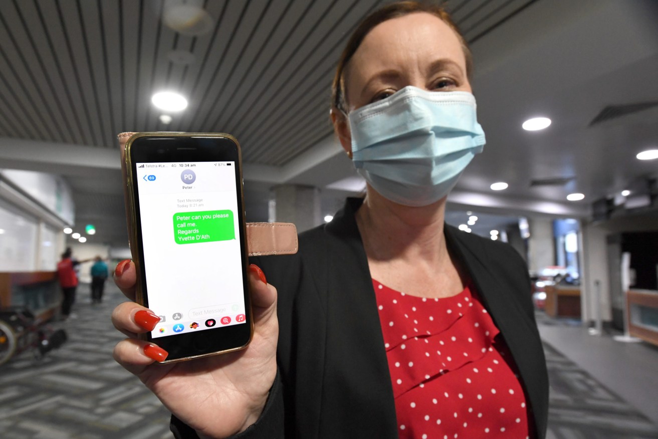 Queensland Health Minister Yvette D'Ath is seen holding her mobile phone showing a text message she attempted to send Defence Minister Peter Dutton amid a row over Queensland's travel restrictions. (AAP Image/Darren England) 