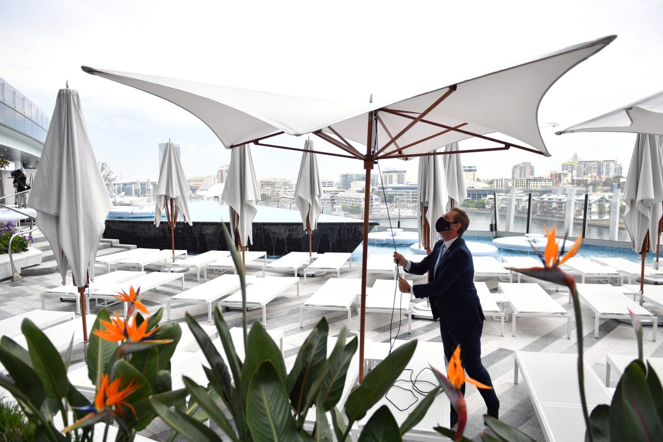 Workers begin reopening preparation by setting up pool umbrellas at Crown Sydney in Sydney, Sunday, October 10, 2021. From Monday, lockdown restrictions will lift for fully vaccinated people across NSW. (AAP Image/Joel Carrett) NO ARCHIVING