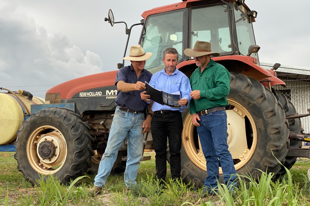 Wide Bay region sugar cane growers Jeffery Plath, left, and Peter McLennan, right, look over the new safety guide with Canegrowers CEO Dan Galligan.