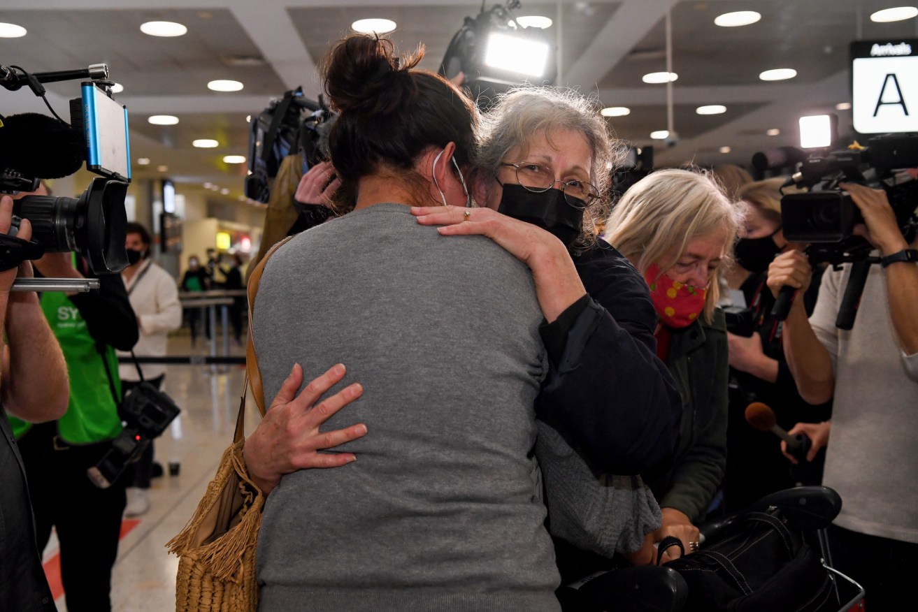 A traveller (right) arriving on one of the first international flights is greeted by her daughter at Sydney International Airport. The first passengers travelling without quarantine restrictions have begun arriving at Sydney. (AAP Image/Bianca De Marchi) 