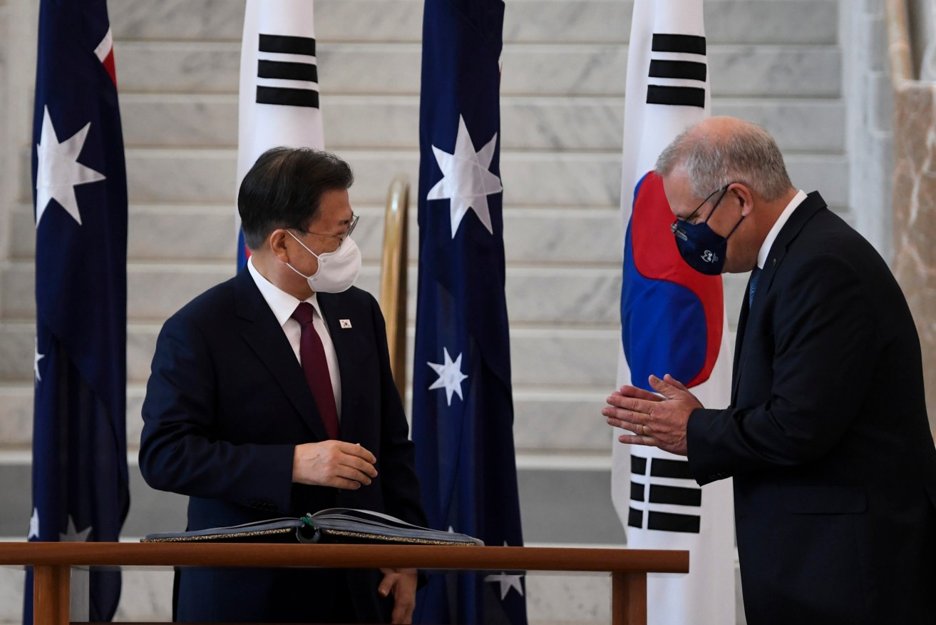 Australian Prime Minister Scott Morrison (right) welcomes South Korean President Moon Jae-in as he signs the official visitors book at Parliament House, Canberra. (AAP Image/Lukas Coch)