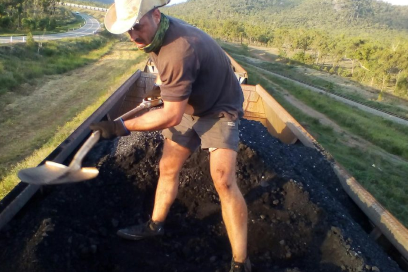 Activist Kyle Magee shovelling coal from an Adani train (courtesy Frontline Action on Coal)