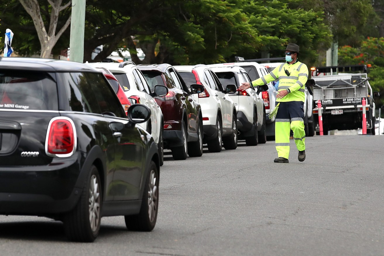 Local residents line up at a drive-in testing center in Brisbane. (AAP Image/Jono Searle) 