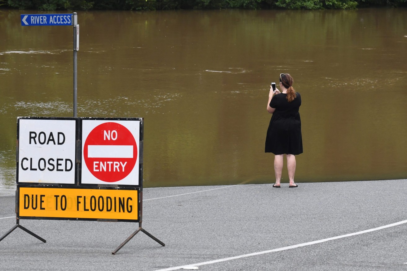 A woman is seen taking a photograph of the flood waters from the Mary River in Gympie, 147 kilometres north of Brisbane, Sunday.  Floodwaters are now receding, leaving a massive clean-up task. (AAP Image/Darren England) 