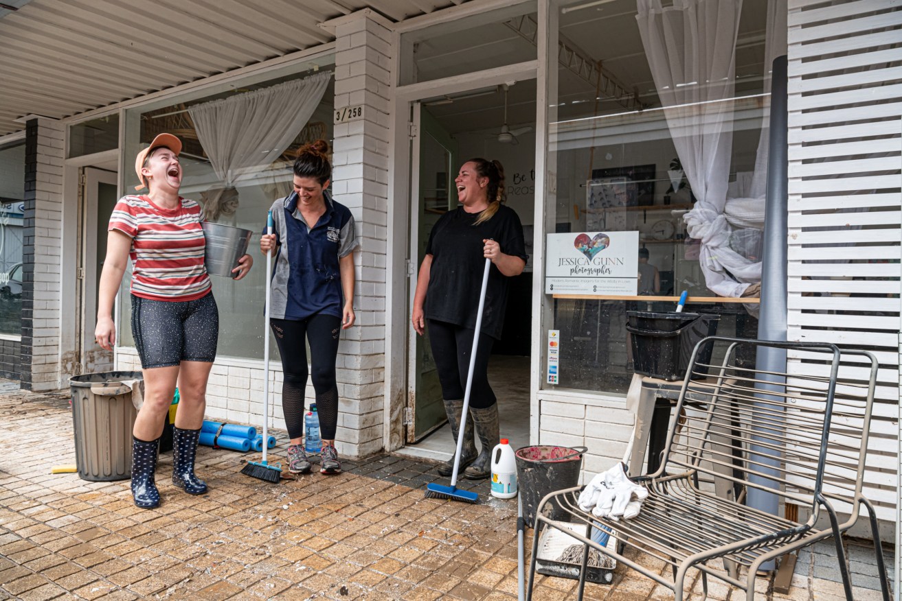 Brittany Robinson, Roxanne Spies and Jessica Gunn react while cleaning up damage from floodwaters in Maryborough on Tuesday. The regional city was devastated when remnants of tropical cyclone Seth dumped 600mm of rain on the Wide Bay-Burnett region in two days. (AAP Image/Paul Beutel) 