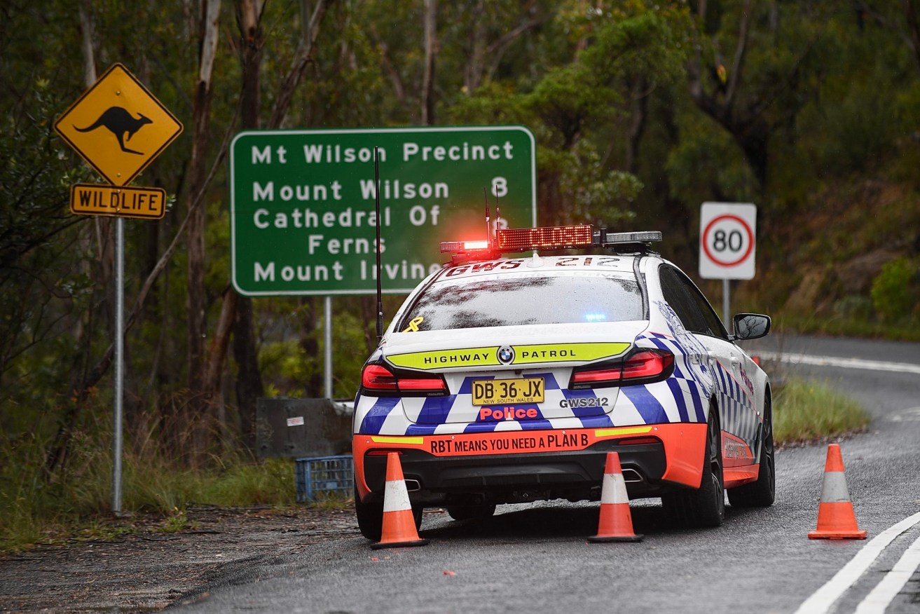 A police roadblock is set up at the entrance of the suburb of Mount Wilson, north of Katoomba, NSW, on Tuesday,. More than 100 police, firefighters and SES volunteers were involved in the search for a nine-year-old girl last seen on Thursday. (AAP Image/Steven Saphore) 