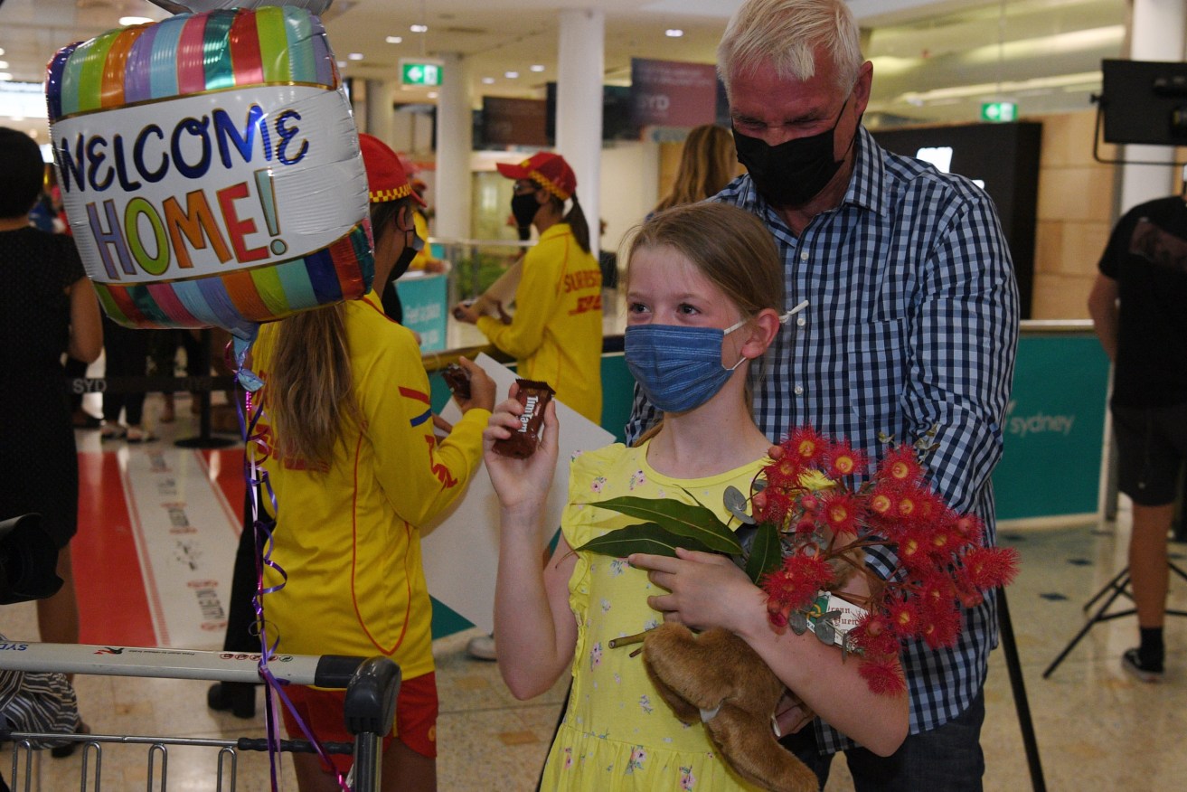 Charlotte Roempke, 8,  welcomes her grand father Bernie Edmonds as he arrives at Sydney International Airport on the first day Australia welcomes fully vaccinated visa holders, tourists, and business travellers. (AAP Image/Dean Lewins) 