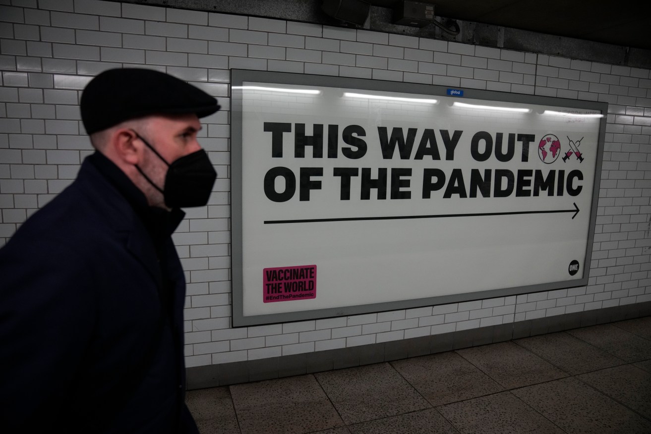  A man wearing a face mask walks past a health campaign poster in an underpass leading to Westminster underground train station, in London. (AP Photo/Matt Dunham, File)