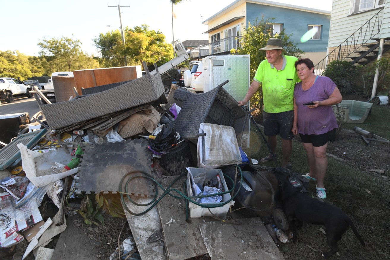 Deagon residents John Puttick and Catherine O'Keeffe among their flood damaged belongings.  (AAP Image/Darren England)