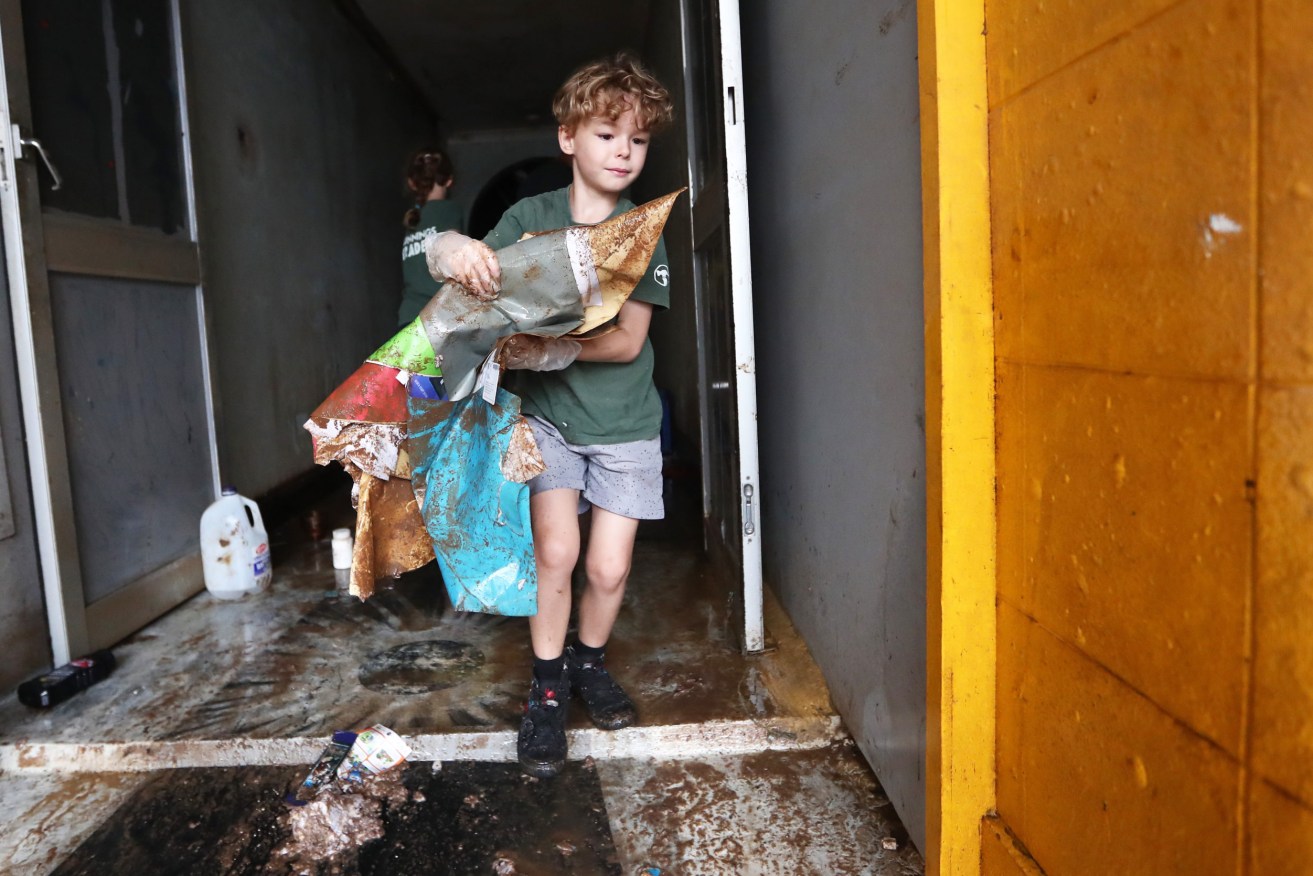 Local boy Sebastian Eyles helping with the clean up in the  Lismore Central Business District  (AAP Image/Jason O'Brien)