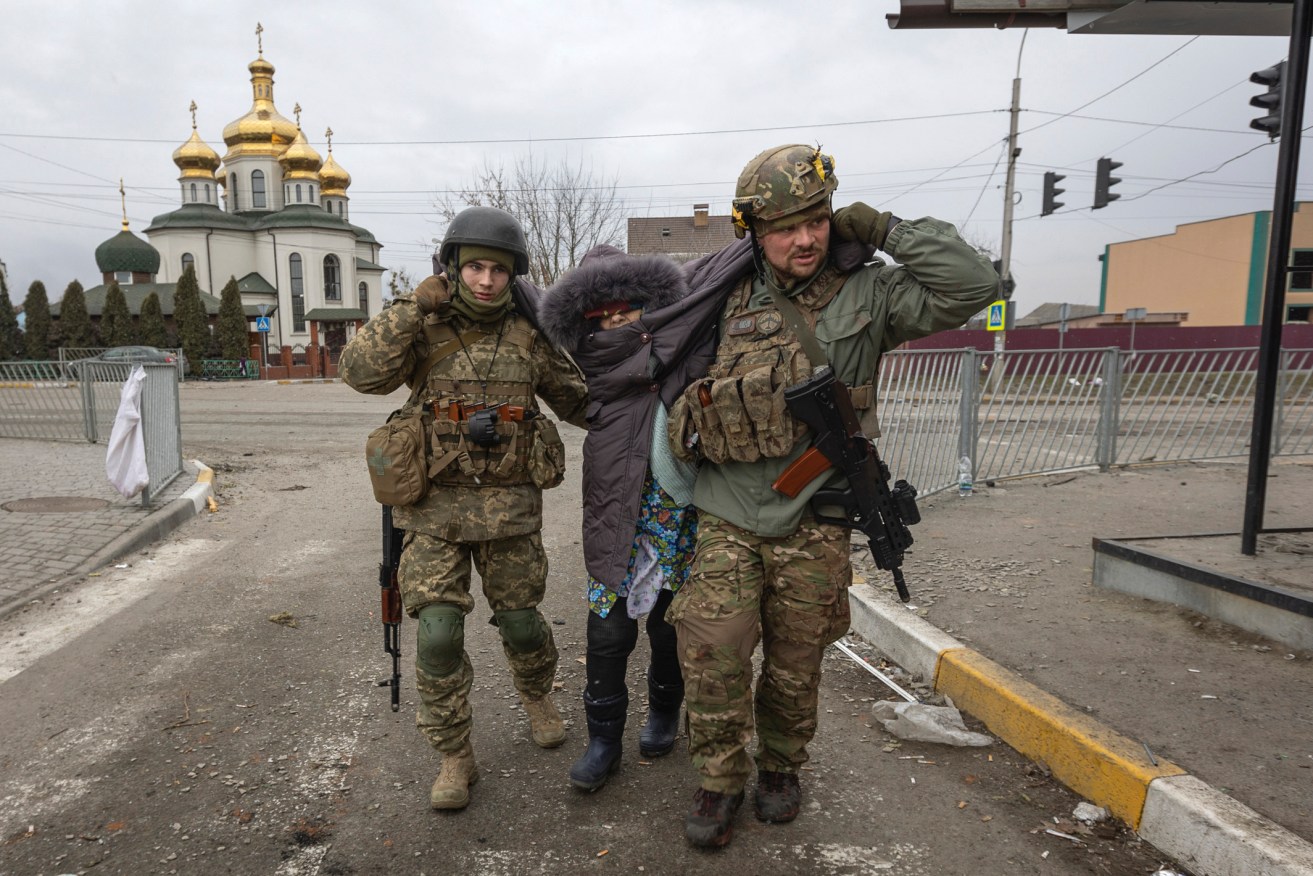 Ukrainian servicemen help an elderly woman, in the town of Irpin, Ukraine. (AP Photo/Andriy Dubchak)