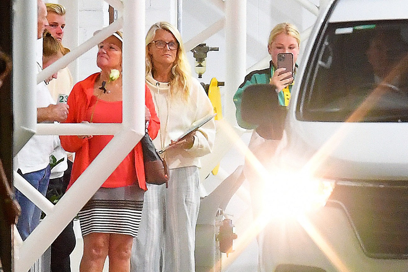 Simone Callahan (centre) ex-wife of Shane Warne looks on as a white van exits from a hangar at Essendon Airport Thursday. Warne's remains had arrived in Melbourne from Thailand. (AAP Image/James Ross) 