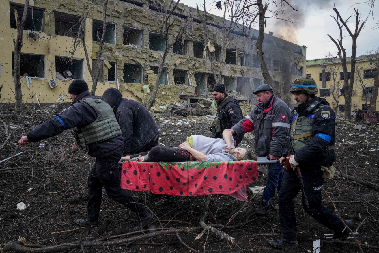 Ukrainian emergency employees and volunteers carry an injured pregnant woman from the damaged by shelling maternity hospital in Mariupol, Ukraine. (AP Photo/Evgeniy Maloletka)