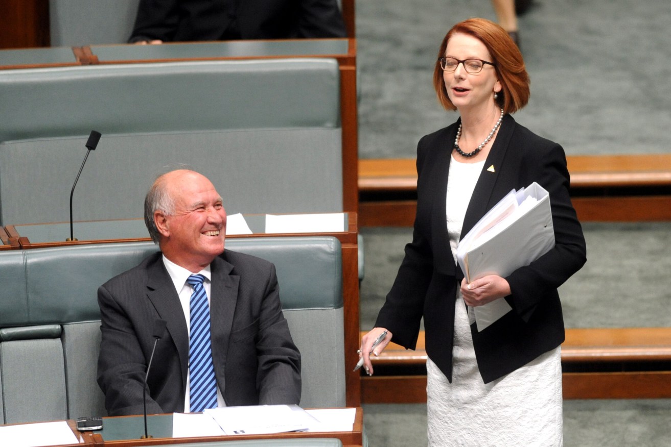Prime Minister Julia Gillard speaks to independent MP Tony Windsor as she arrives for House of Representatives question time at Parliament House in Canberra, Tuesday, March 12, 2013. (AAP Image/Alan Porritt) 