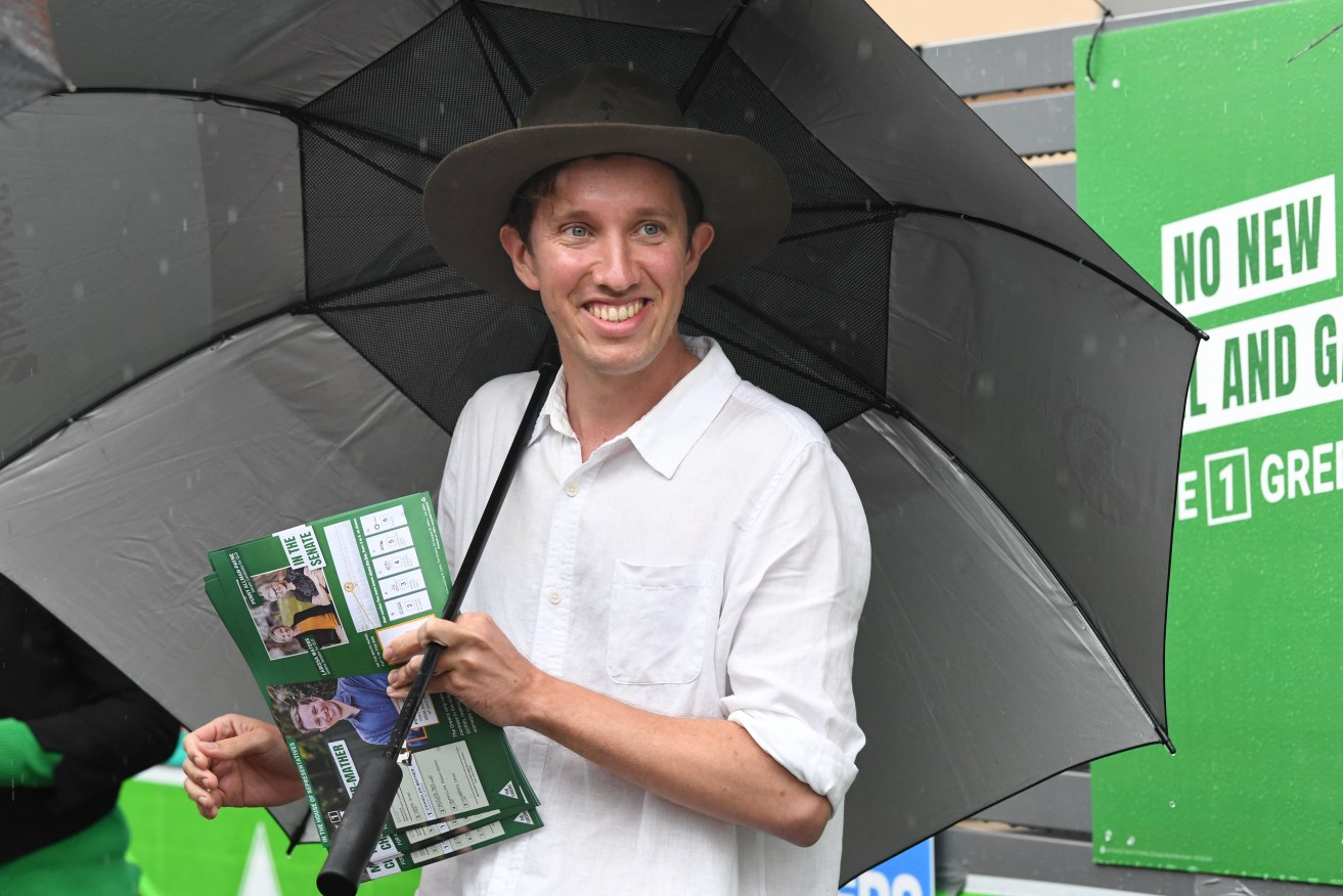 Max Chandler-Mather, Greens candidate in the seat of Griffith is seen handing out how to vote leaflets at the Brisbane State High polling booth on Federal Election day in Brisbane. (AAP Image/Darren England) 