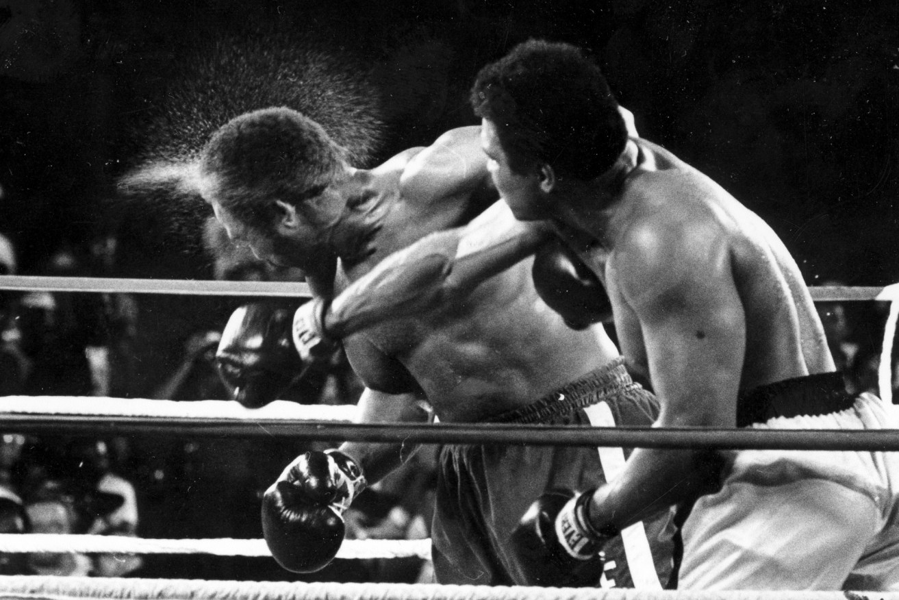 Perspiration flies from the head of George Foreman as he takes a right from challenger Muhammad Ali in the seventh round in the match dubbed Rumble in the Jungle in Kinshasa, Zaire.  Foreman was knocked out in the eighth round. It was 40 years ago that two men met just before dawn on Oct. 30, 1974, to earn $5 million in the Rumble in the Jungle. In one of boxing's most memorable moments, Muhammad Ali stopped the fearsome George Foreman to recapture the heavyweight title in the impoverished African nation of Zaire.  (AP Photo/Ed Kolenovsky, File)