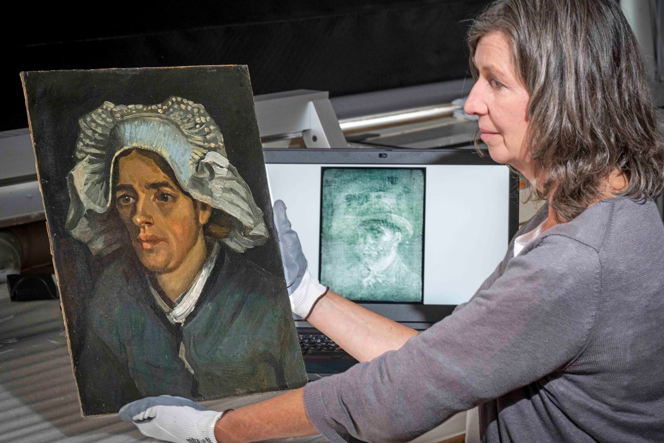 Senior Conservator Lesley Stevenson views Head of a Peasant Woman alongside an x ray image of the hidden Van Gogh self portrait. (Neil Hanna via AP)