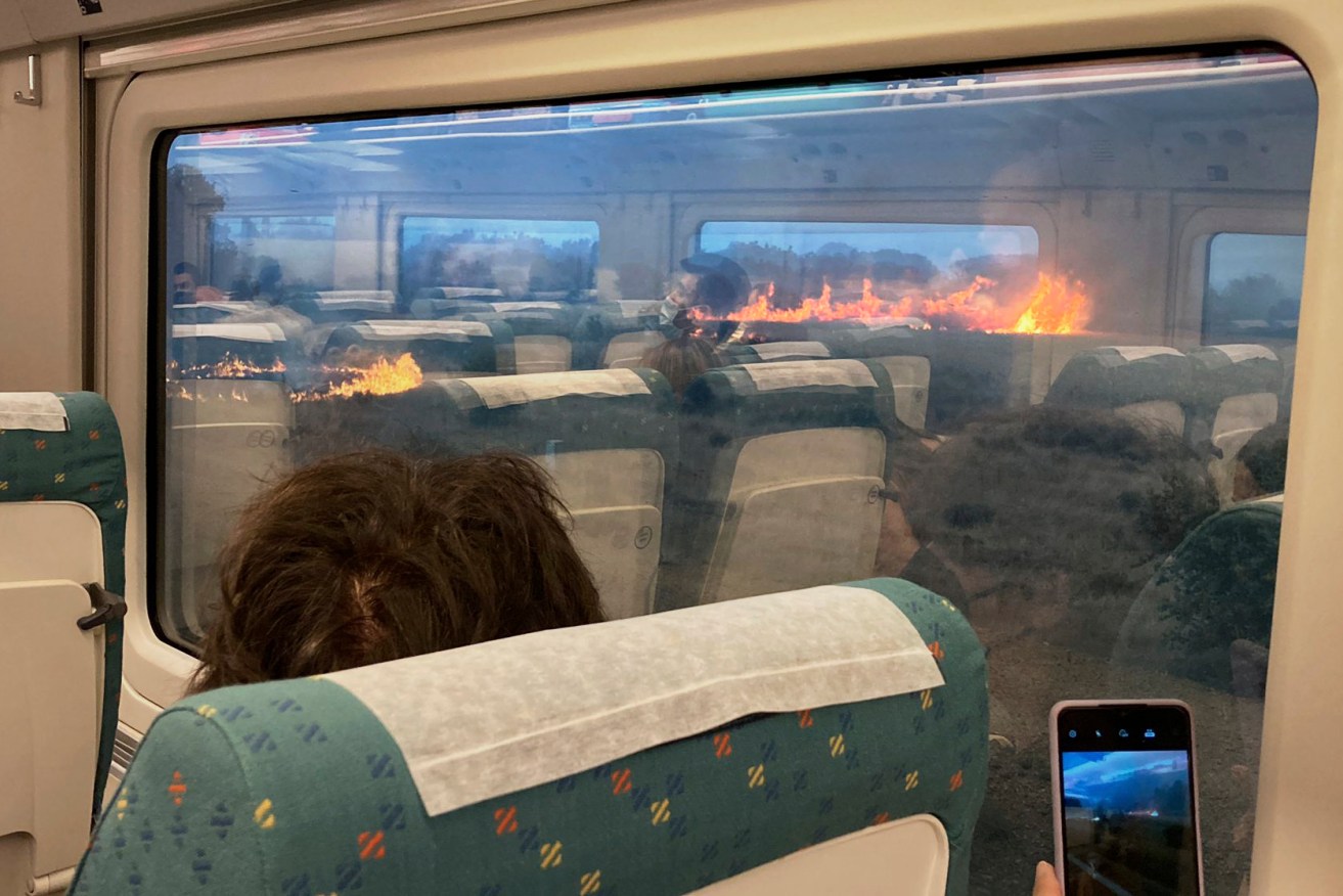 Passengers take photos at a wildfire while traveling on a train in Zamora, Spain, Monday, July 18, 2022. When Francisco Seoane's train unexpectedly stopped in Spanish countryside that was being engulfed by a wildfire, he and other passengers got a fright when they looked out at flames encroaching on both sides of the track. The Spaniard told The Associated Press it was scary to see how quickly the fire spread. Video of the unscheduled — and unnerving — stop shows about a dozen passengers in Seoane's railcar appearing alarmed as they look out of the windows Monday. (AP Photo/Francisco Seoane Perez)