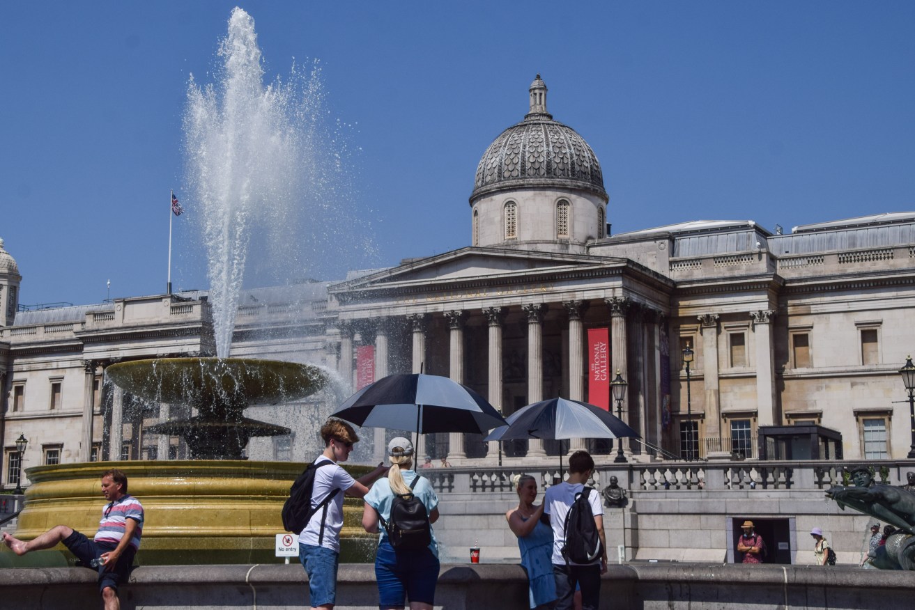 People shield themselves from the sun with umbrellas in Trafalgar Square as the UK records its highest ever temperatures. The Met Office has issued its first-ever red warning over extreme heat in the UK. (Photo by Vuk Valcic / SOPA Images/Sipa USA)